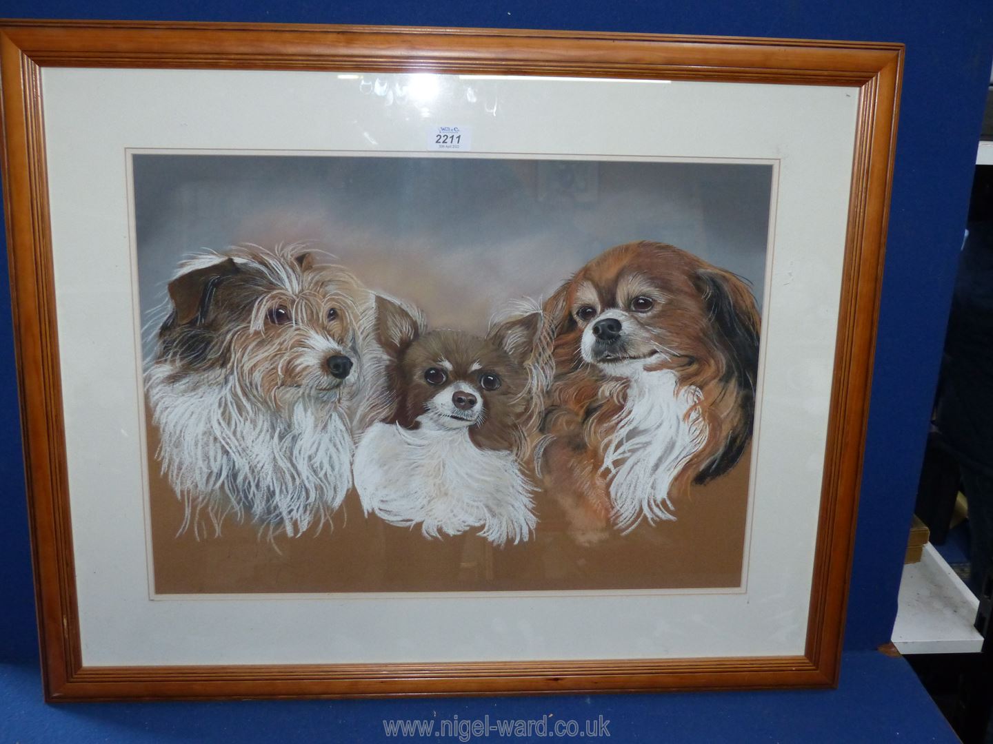 A framed and mounted pastel painting depicting three small dogs, signed lower left L.