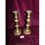 A pair of brass candlesticks with pushers.