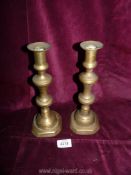 A pair of brass candlesticks with pushers.