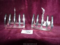 A pair of silver four division toast racks of arched form having centre carrying handle,