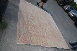 A large cream, pale coral and beige bordered, patterned and fringed Carpet,