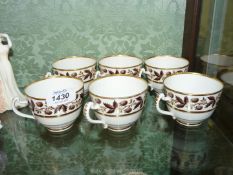 Six Derby teacups with berry and foliage decorated borders with gold highlights.