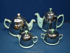 An Art Deco four piece Teaset with chrome insulating covers and green floral detail.