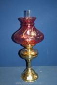 A Brass finished Oil Lamp with ornate pink glass shade and clear glass chimney, 22'' tall.