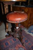 A Walnut Piano Stool with leather cushioned seat.