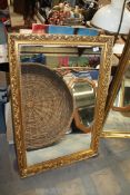 A large wall Mirror in engraved and raised leaf design gilt frame, 39'' x 27''.