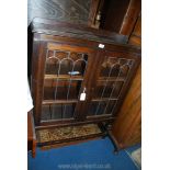 An dark Oak floor standing Bookcase having a pair of opposing leaded glazed doors and standing on