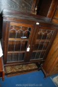 An dark Oak floor standing Bookcase having a pair of opposing leaded glazed doors and standing on