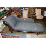 A circa 1900 darkwood framed Chaise Longue upholstered in dark grey fabric and standing on turned