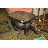 A low hard-wood seat/occasional table, the base being fashioned as a carved Rhinoceros,