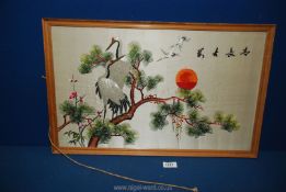 A Japanese embroidered picture on silk depicting Cranes in a tree at sunset.