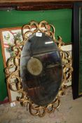 An oval bevel edged mirror with gilded scrolling framework 27" x 20".