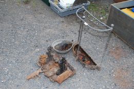 A metal boot scraper, metal umbrella stand and cattle drinker bowl.