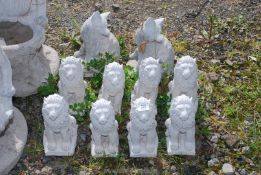 Eight small concrete lions and two small foxes.