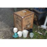 An old tea chest with various sized plastic pots and china pots.