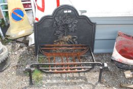 A fire back with a fire basket having horse and tree decoration.