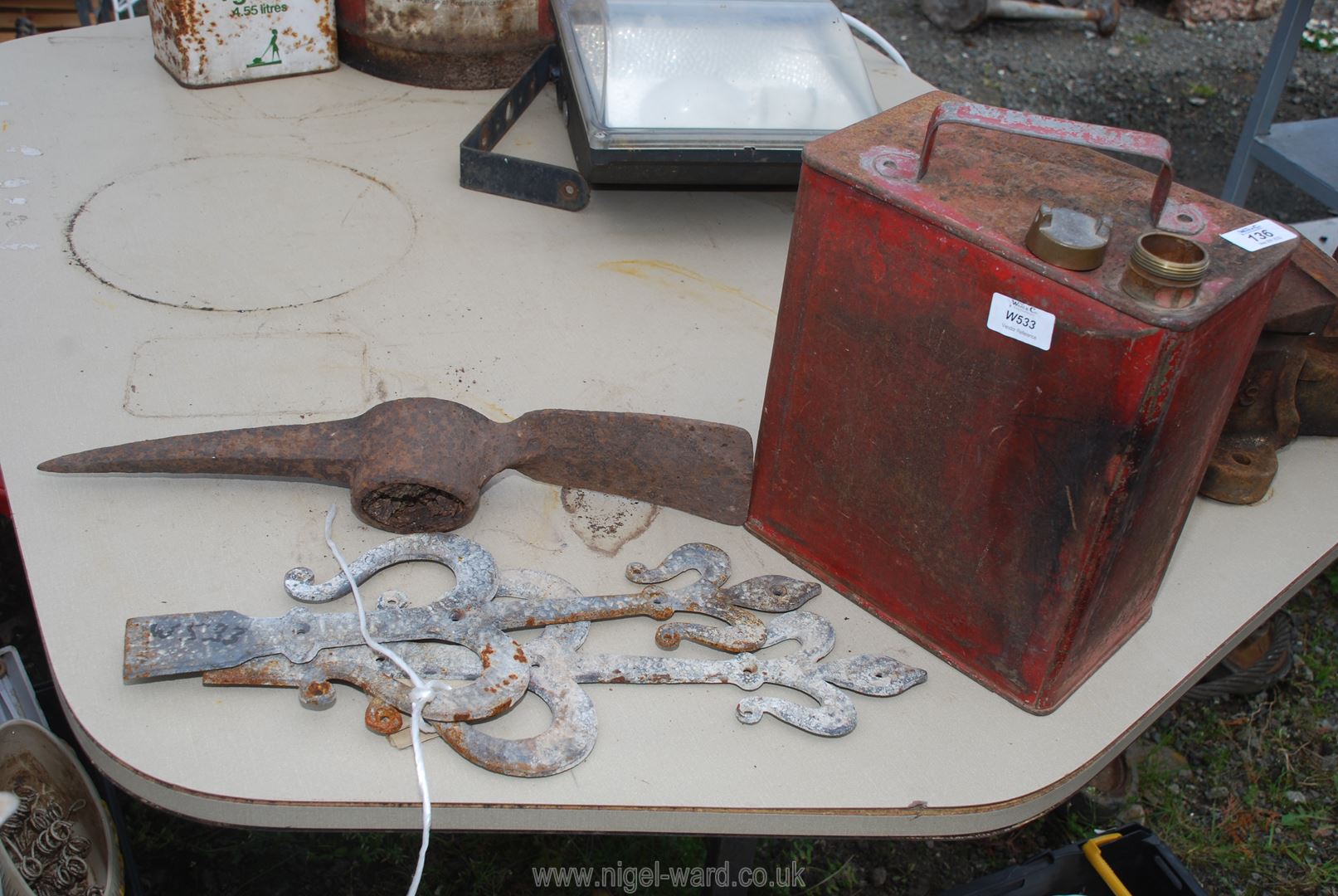 A petrol fuel can with brass top, flat iron scroll features and pick axe head.