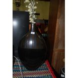 A large black and gold bottle vase and artificial flowers
