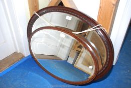 Two darkwood framed oval mirrors.