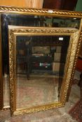 A gold coloured scrolling foliage decorated framed bevelled wall mirror,