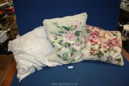 A lace cushion and two needlepoint cushions.