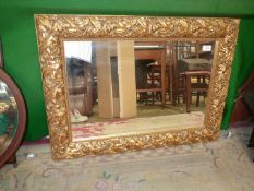 A gilt framed bevel edge wall mirror with raised leaf detail to the frame,