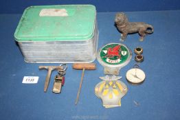 An aluminium tin and contents including AA badge, Wales enamel car badge, compass, brass lion,