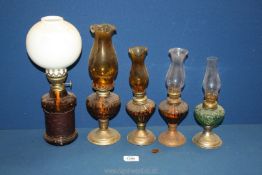 A quantity of small oil lamps with amber coloured reservoirs,