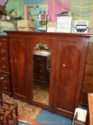 A circa 1900 Triple Wardrobe having arched central mirrored door flanked by arched panelled doors