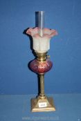 An Oil lamp on reeded column with square base, cranberry glass reservoir and frosted glass shade,