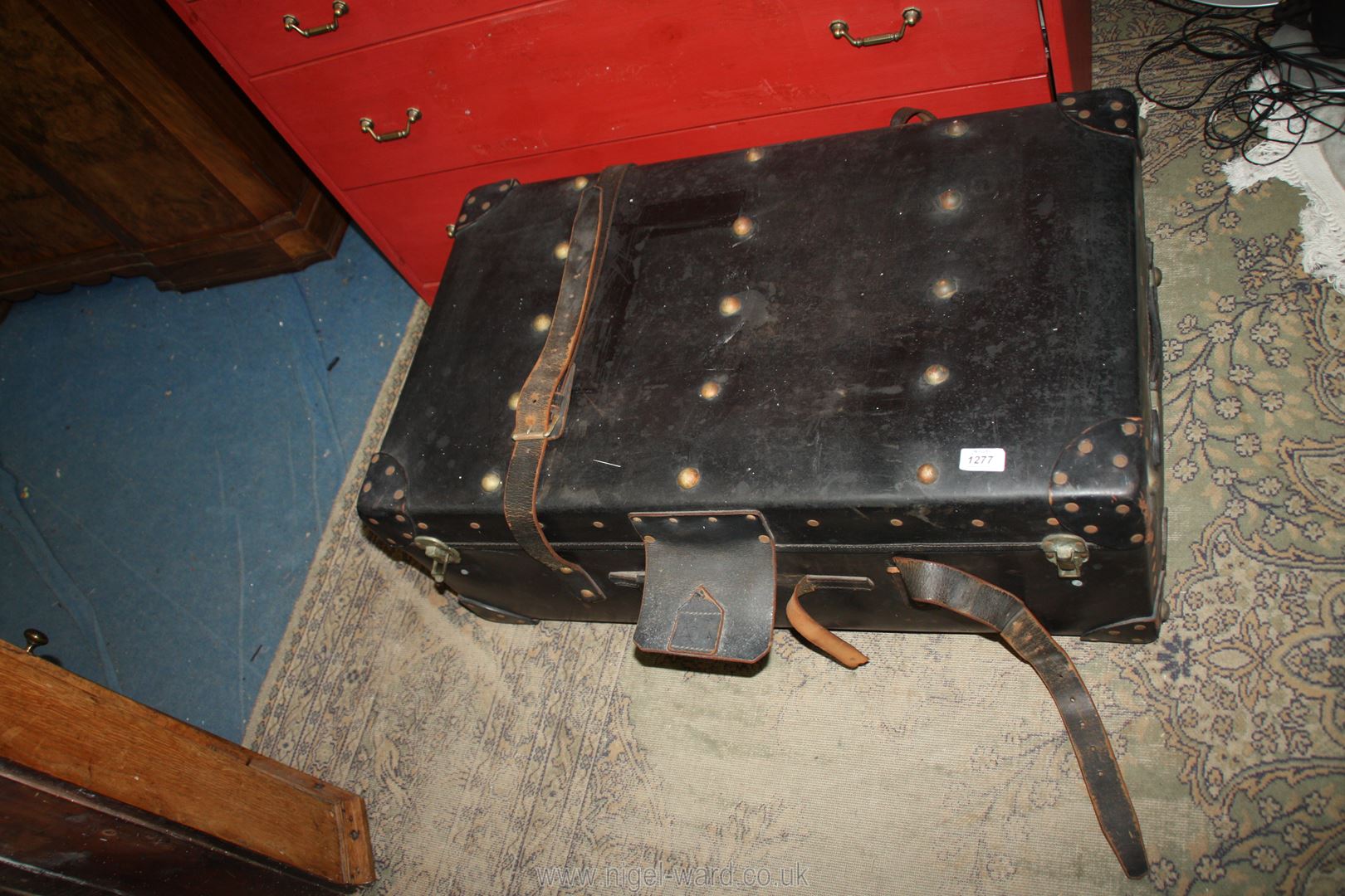 A large black leather Travel trunk with studs and straps having shelf inside (handle missing),