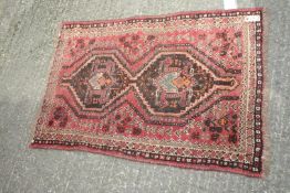 A small Iranian Shiraz wool rug, red/brown, having border pattern and fringing 48" x 32".