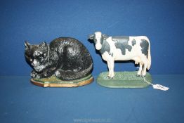 A heavy metal doorstop of a Friesian cow, plus another of a reclining black cat.