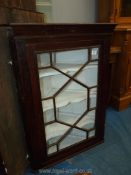 A dark Oak wall hanging Corner Cabinet having a 13 pane geometrically glazed door,