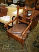 A satinwood framed open armed Commode Armchair having a caned seat,