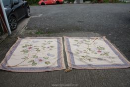 A pair of fabric table covers, cream with blue pattern and floral pattern to centre,