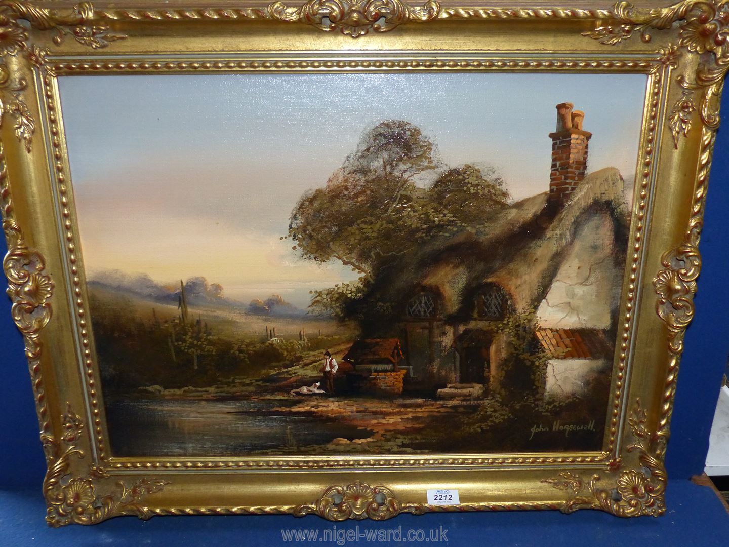 A framed oil on canvas depicting a gentleman and his dog by a well and cottage,