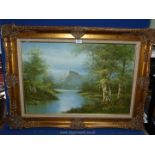 A large gilt framed river landscape with tree lined banks and rocky mountains in the distance.