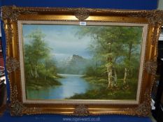 A large gilt framed river landscape with tree lined banks and rocky mountains in the distance.