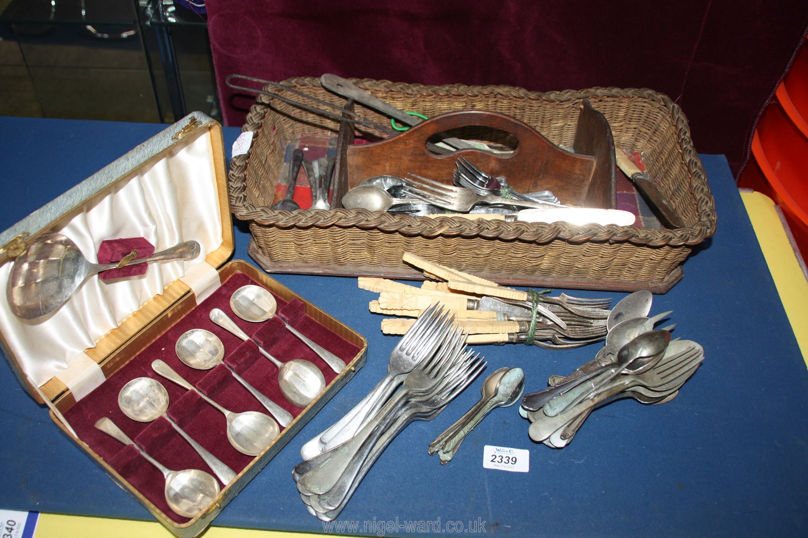 A wicker cutlery tray with assorted bone handled cutlery, spoons, forks and a boxed dessert set.