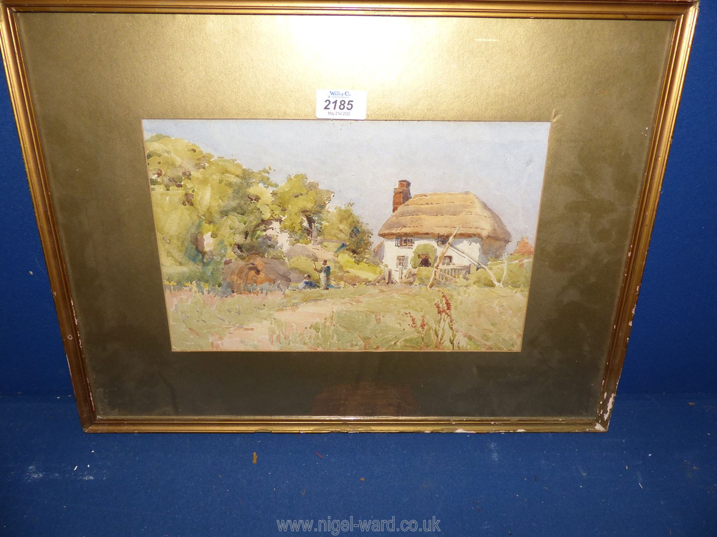 A framed and mounted Watercolour depicting a thatched cottage with figures in the garden.