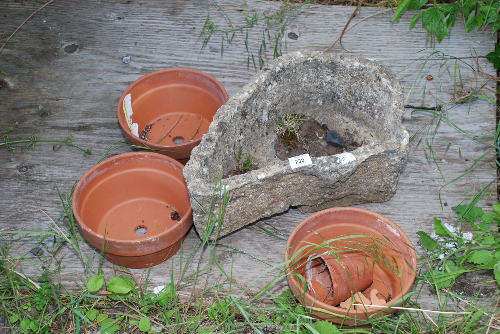A rustic concrete planter with terracotta pots.