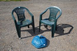 An umbrella stand and two green plastic chairs.