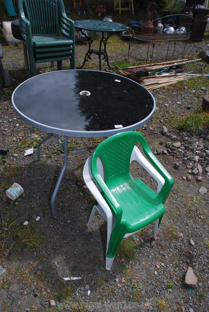 A glass topped table, 34" diameter with two plastic children's chairs.