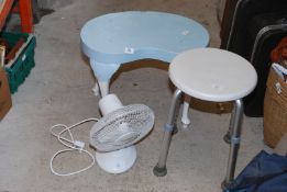 A kidney shaped table, stool and fan heater.