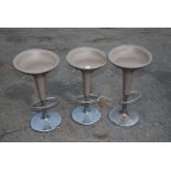 Three retro bar stools on chrome bases by Magis with beige coloured seat.