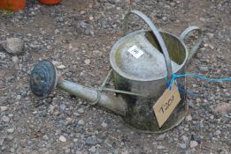 A small galvanised watering can with rose.