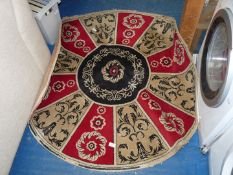 A circular rug in black, red and beige colour.