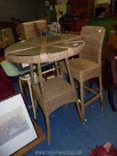 A glass topped wicker bar table with matching chair, 31" diameter x 43" high.