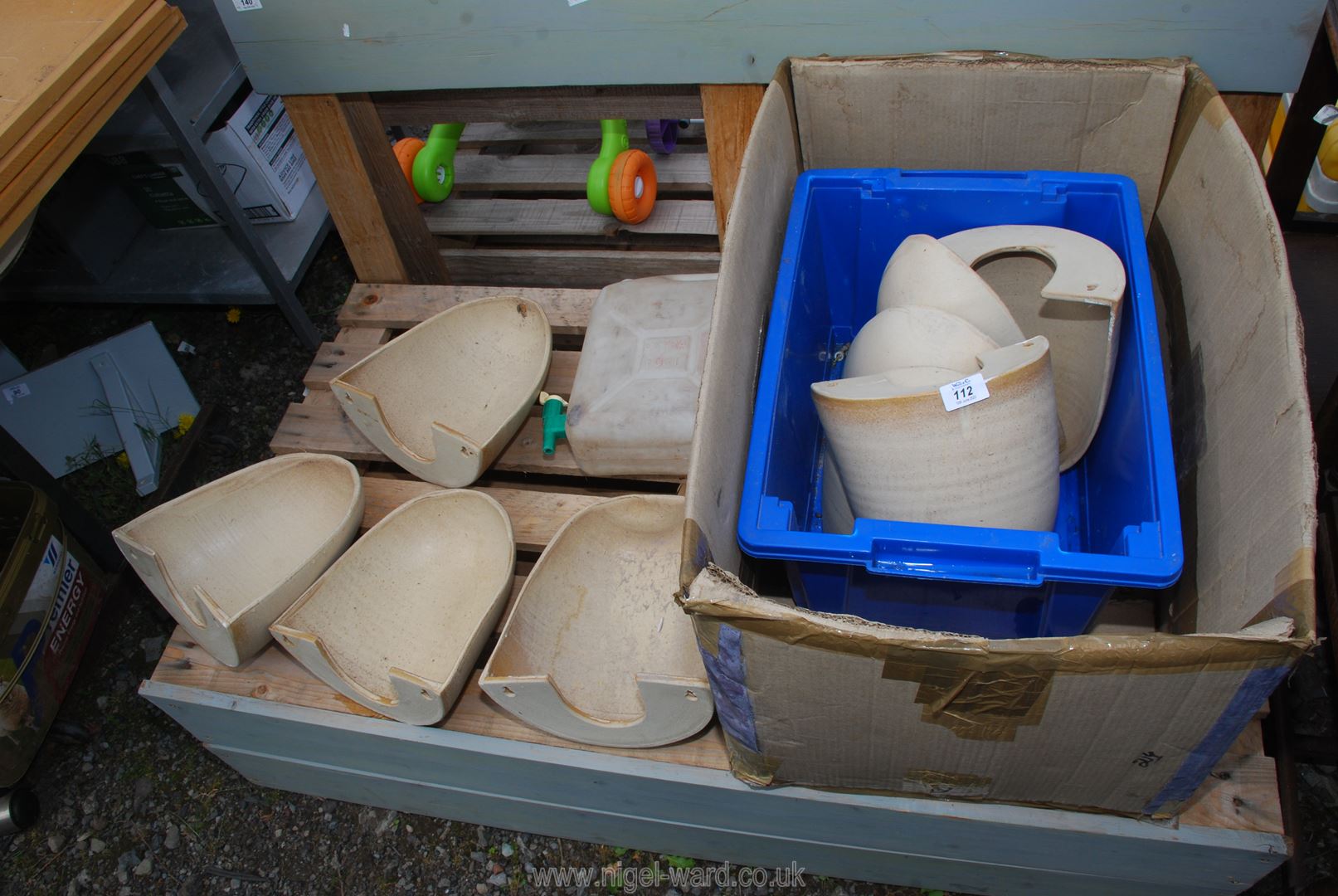 Nine pottery wall mounted planters and a water container.